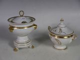 deux vases blancs et dorés posés sur une table blanche