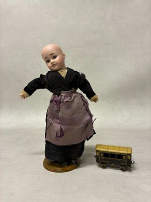 une poupée qui se tient à côté d'un petit train