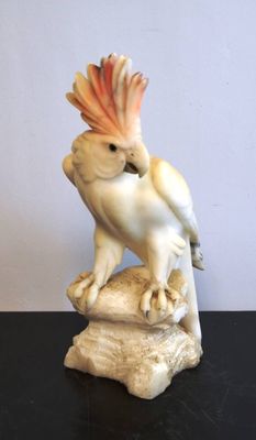 une figurine représentant un cacatoès posé sur un rocher