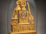 a gold clock under a glass dome on a table