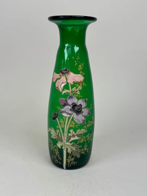 un vase vert orné de fleurs, posé sur une surface blanche