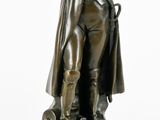 statue d'un homme coiffé d'un chapeau et vêtu d'un manteau, assis sur un socle en marbre
