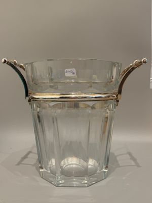 un vase en verre muni d'une poignée en argent, posé sur une table