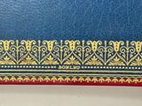 blue leather with gold and red trim on a white surface