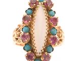 un gros plan d'une bague ornée d'une pierre blanche entourée de pierres roses et bleues