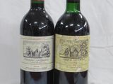 two bottles of wine sitting next to each other on a white surface