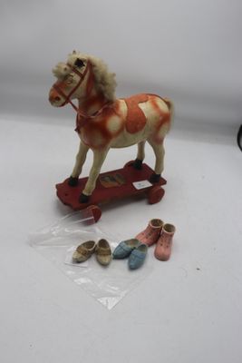 un petit cheval en peluche sur un skateboard, à côté d'une paire de chaussures de bébé