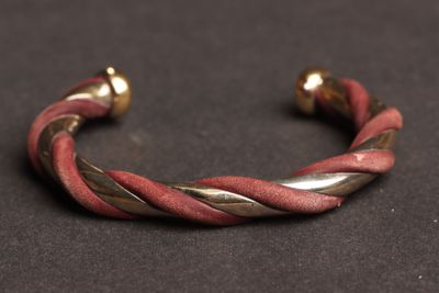 un gros plan d'un bracelet rouge et doré posé sur une surface noire