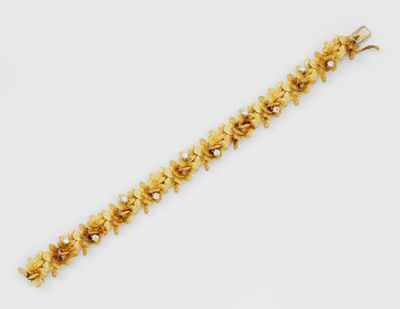 un bracelet en or orné de fleurs et de perles sur fond blanc