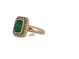 a close up of a gold ring with an emerald stone and diamonds