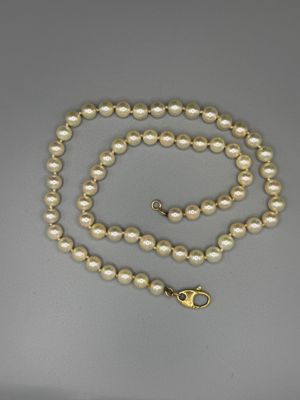 Gros plan sur un collier de perles blanches avec un fermoir en or