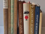 several old books are lined up on a shelf in front of a white wall