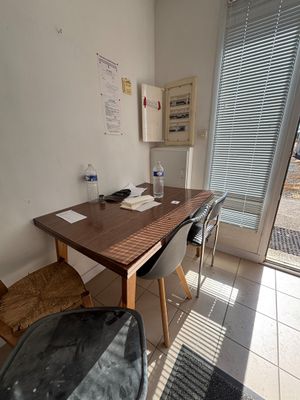 une table en bois avec deux chaises et une chaise placée devant une fenêtre