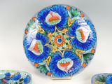 a blue plate with a flower design on it next to two bowls and a spoon