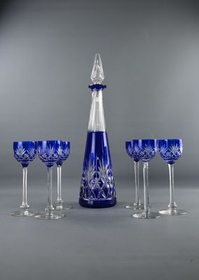 four wine glasses and a decanter on a table