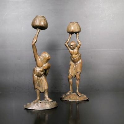 paire de figurines anciennes en bronze représentant un homme et une femme tenant des cruches d'eau