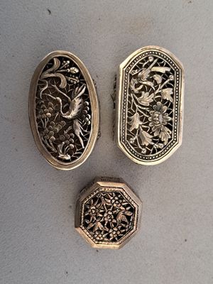 three antique silver lockes sitting on top of a white surface