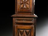 une vieille armoire en bois à deux portes, surmontée d'une horloge