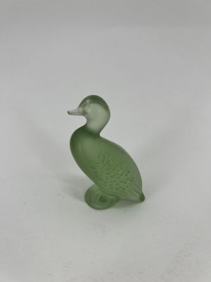 a green glass duck figurine sitting on a white surface