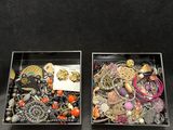 two trays filled with assorted jewelry on a black surface