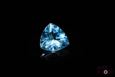 un diamant bleu dans l'obscurité, sur une surface noire