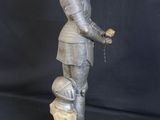 statue of a man in a suit of armor with a dog on a rock