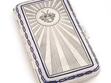 a silver cigarette case with a picture of a sunburst on it