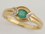 gros plan d'une bague en or avec une pierre verte et des diamants