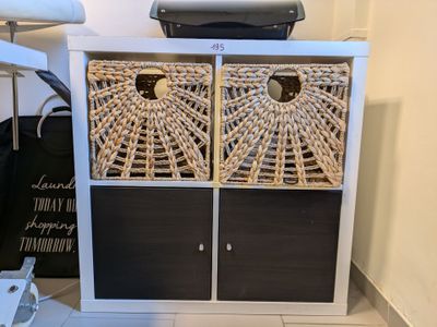 une armoire blanche surmontée de paniers en osier