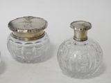 three glass jars with silver lids sitting on top of a white surface