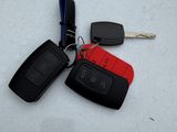 two car keys and a remote control on a white surface