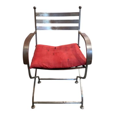une chaise en métal sur laquelle est posé un coussin rouge