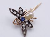 a close up of a brooch with a pearl and a flower