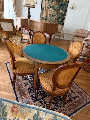 une table et des chaises dans un salon, avec un piano en arrière-plan