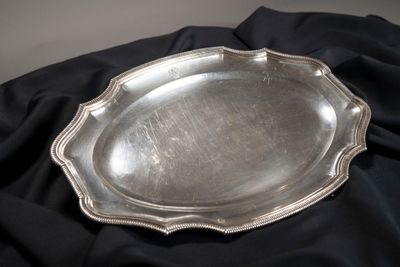 une assiette en argent posée sur un napperon noir, sur fond noir