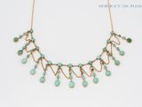 a gold necklace with turquoise stones on a white background