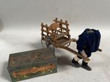 un petit bonhomme tirant une charrette en bois sur laquelle se trouve une caisse en bois