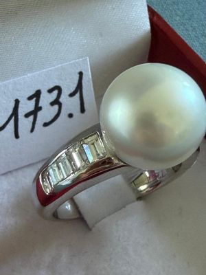 une bague en perle blanche dans un coffret rouge avec une étiquette de prix