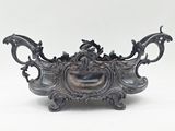 un vase en argent orné d'un dragon sur un fond blanc