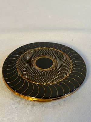 une assiette noire et dorée ornée d'un motif circulaire