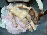 a doll that is laying on a chair with a pink dress