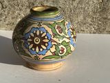 un petit vase posé sur une table, avec un mur en pierre en arrière-plan
