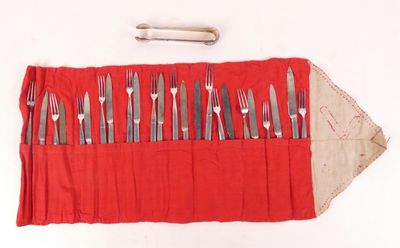 un rouleau rouge sur lequel sont posés des couverts, ainsi qu'un couteau et une fourchette