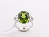 a green tourmaline and diamond ring on a white background