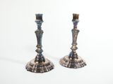 pair of silver candlesticks on a white surface with a white background