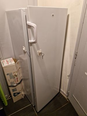 un réfrigérateur blanc dans un coin de la pièce, près d'un mur