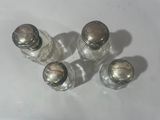 four salt shakers are sitting on a white table top