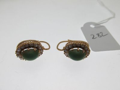a pair of gold and jade earrings