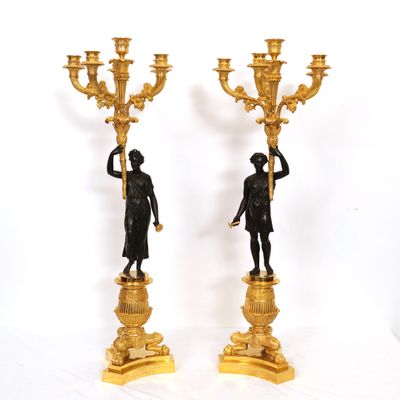 pair of antique bronze figurines of a man and a woman holding a candelabra