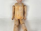an old wooden doll sitting on a white surface with a pair of brown shoes